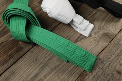 Photo of Colorful karate belts on wooden background, closeup