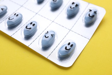 Photo of Antidepressants with happy emoticons on yellow background, closeup