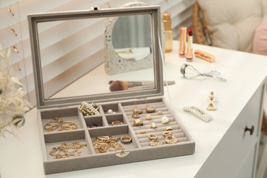 Photo of Elegant jewelry box with beautiful bijouterie on commode indoors