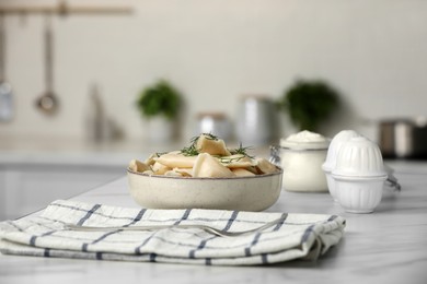 Photo of Delicious dumplings with dill on table in kitchen