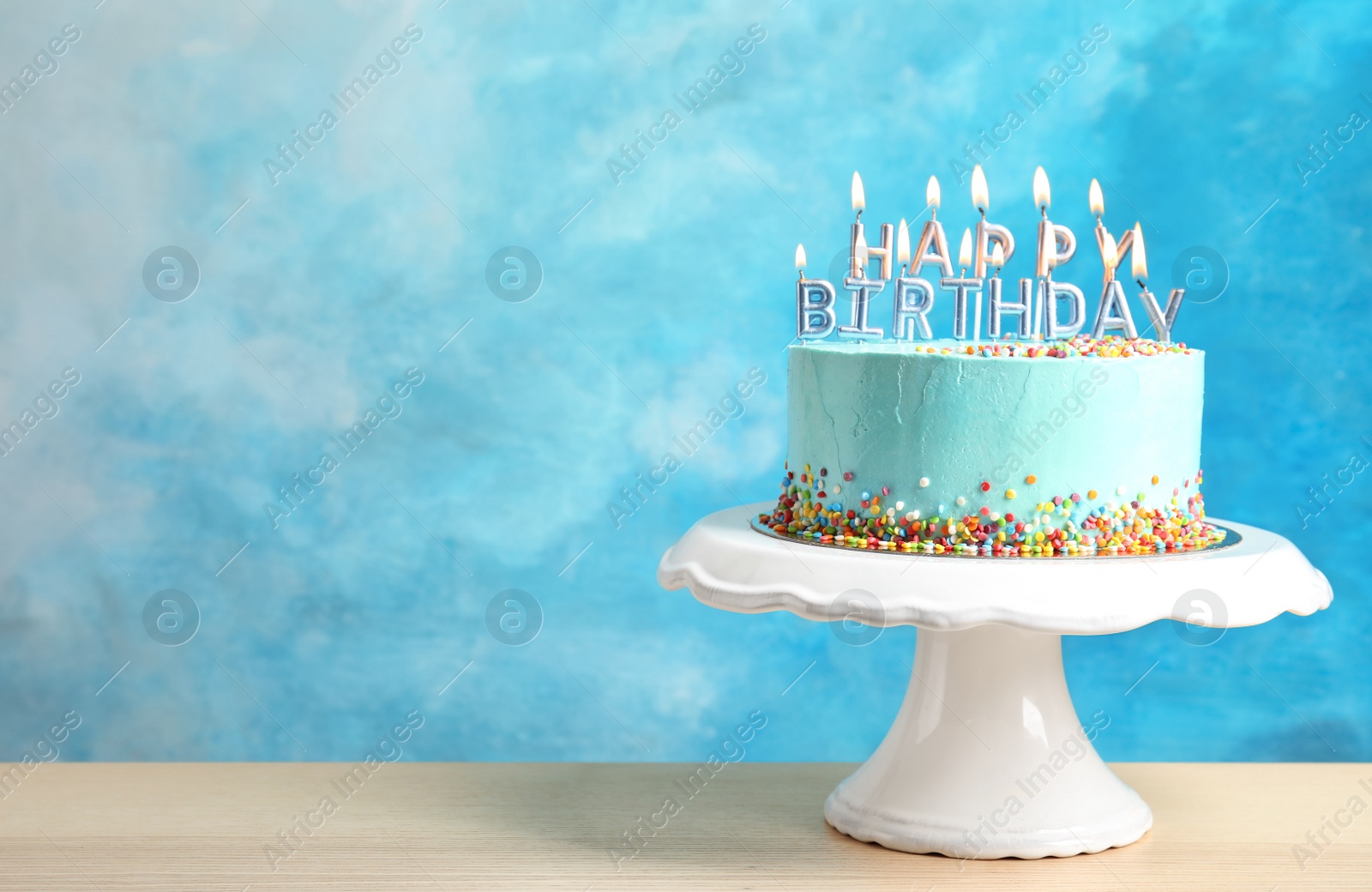 Photo of Fresh delicious birthday cake with candles on stand against color background. Space for text