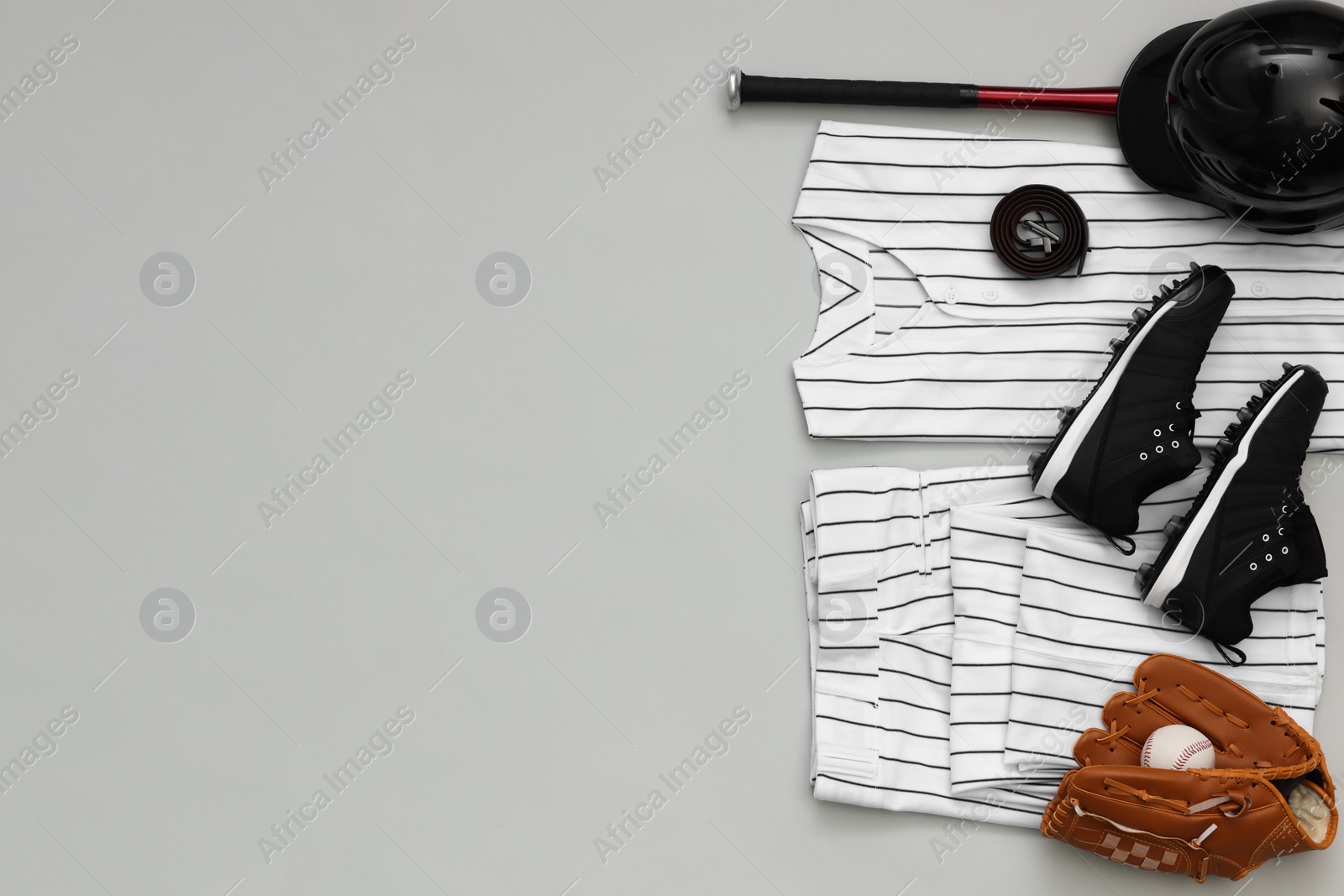 Photo of Baseball uniform and other sports equipment on white background, flat lay. Space for text