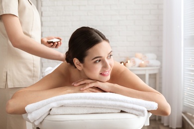 Young woman having body scrubbing procedure with sea salt in spa salon