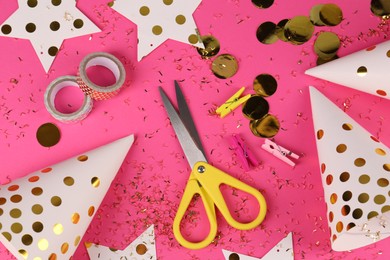 Photo of Party hats with confetti, paper stars, scissors and tapes on pink background, flat lay. Handmade decorations