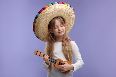 Cute girl in Mexican sombrero hat playing ukulele on purple background