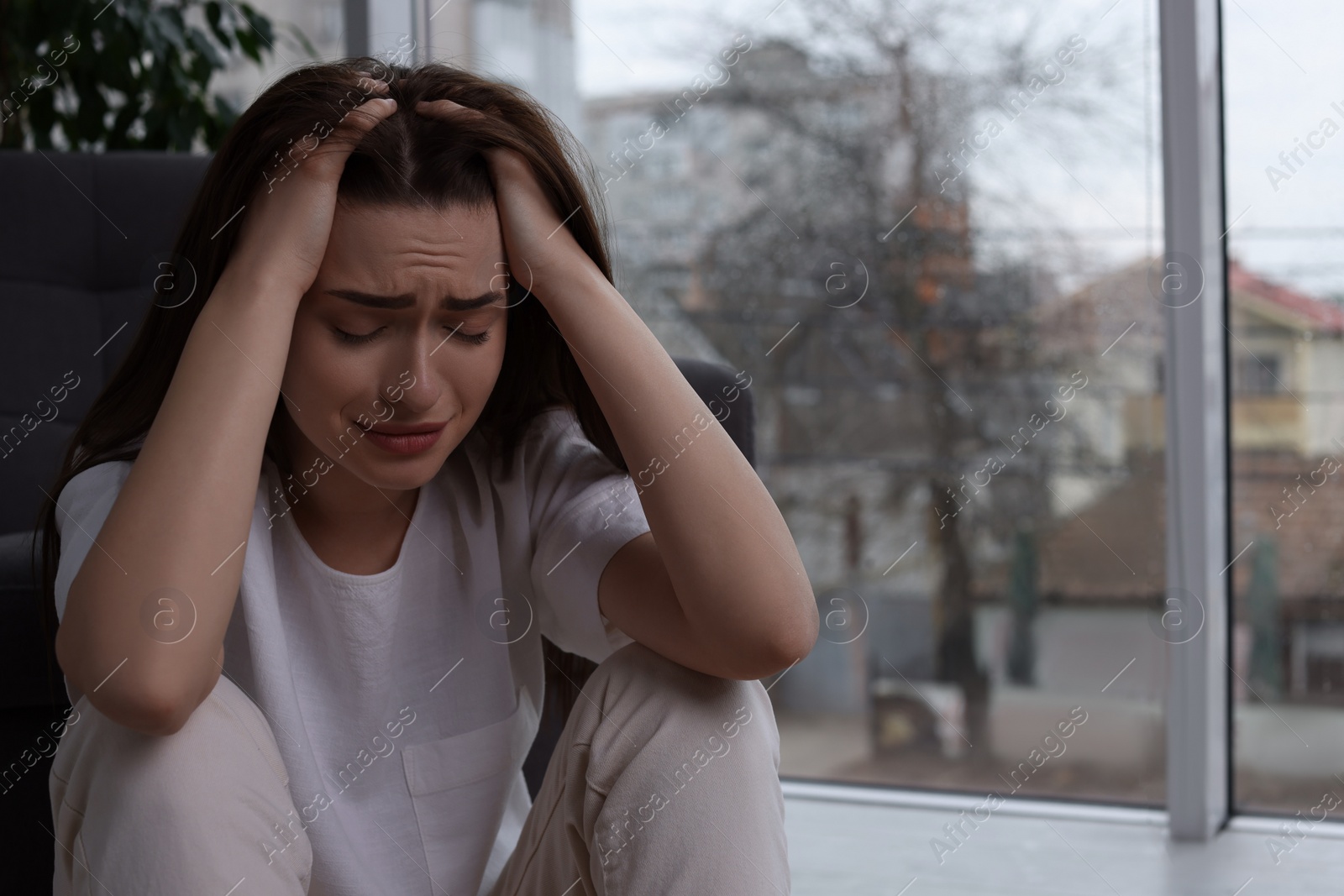 Photo of Sad young woman crying at home, space for text. Loneliness concept