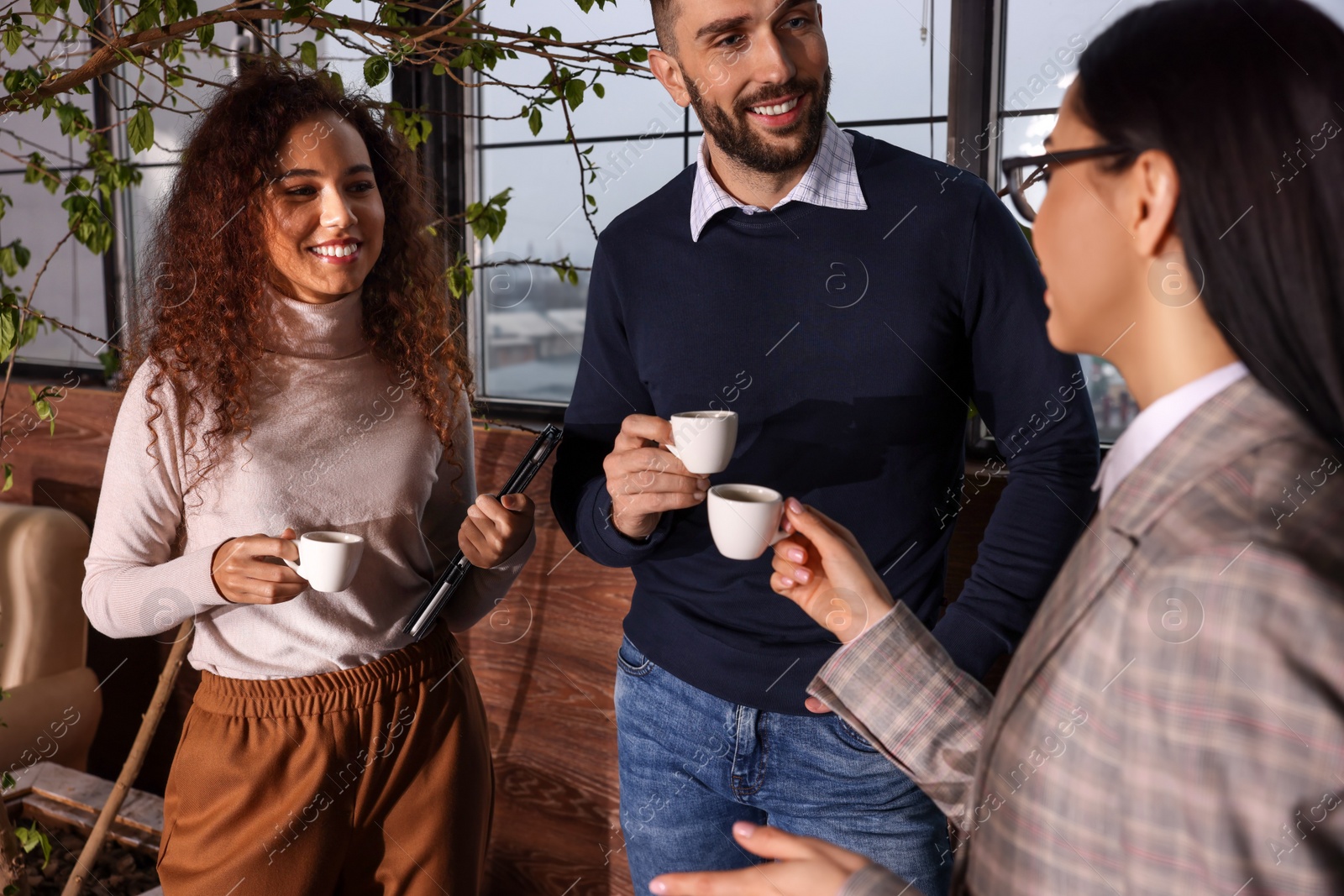 Photo of Group of coworkers talking during coffee break in office