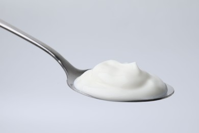 Photo of Delicious natural yogurt in spoon on light background