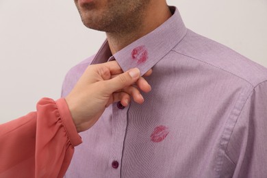 Photo of Woman noticed lipstick kiss marks on her husband's shirt against white background, closeup