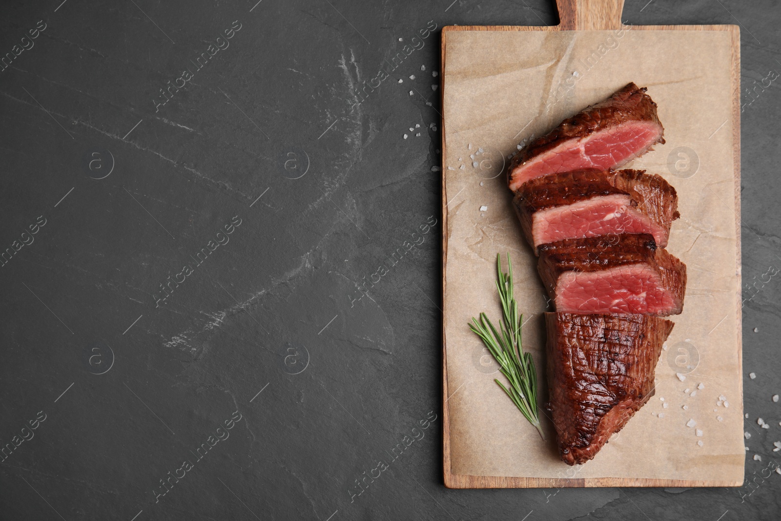 Photo of Delicious sliced beef tenderloin served on black table, top view. Space for text