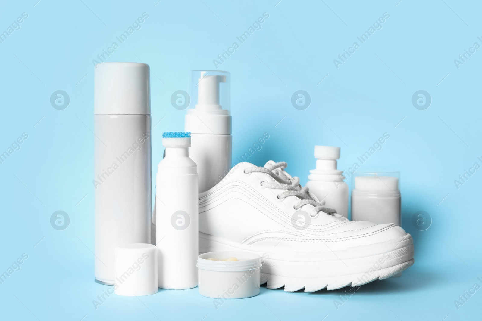 Photo of Composition with stylish footwear and shoe care accessories on light blue background