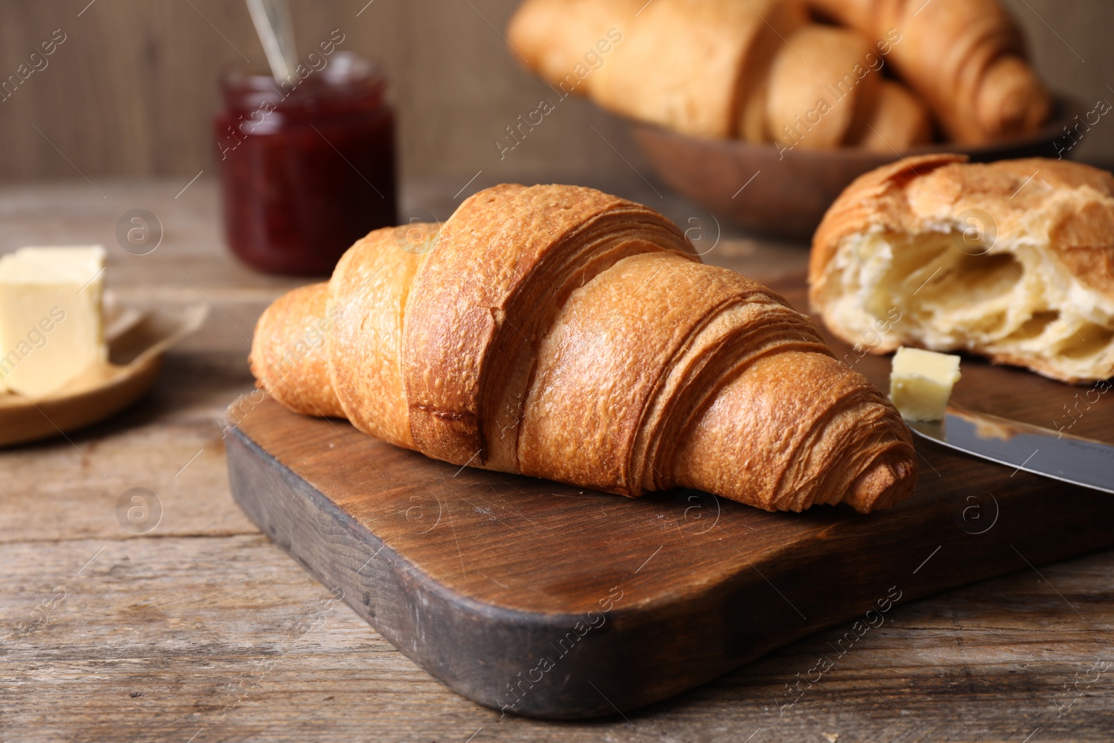 Photo of Tasty fresh croissants on wooden table, closeup