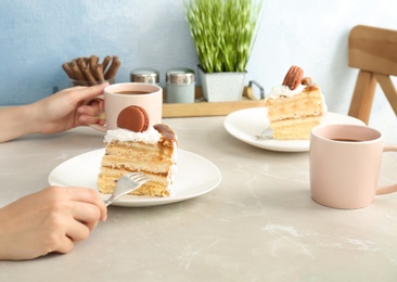 Photo of Woman eating delicious homemade cake with caramel sauce at table