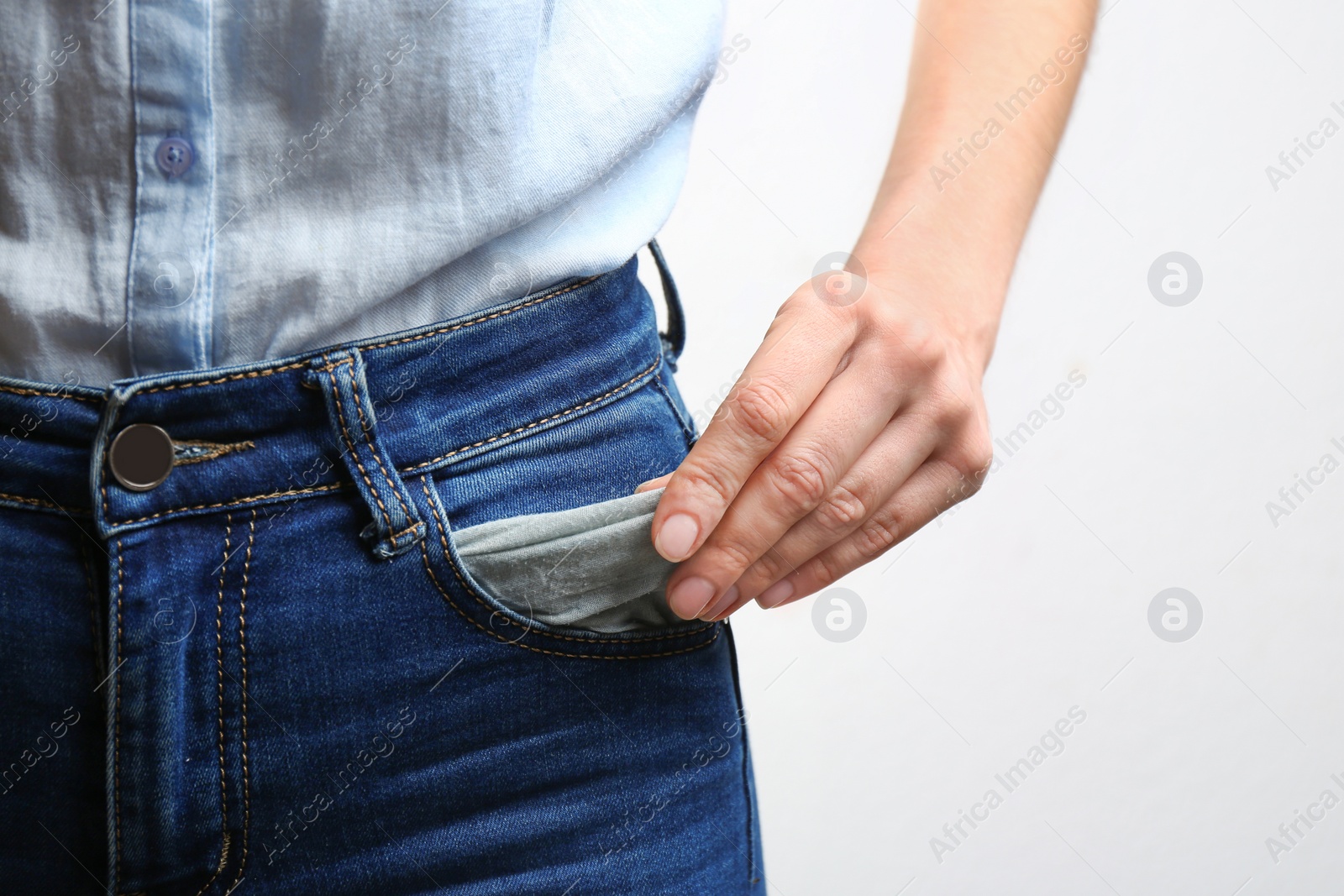 Woman showing empty pocket on light background, closeup Photo of Woman showing empty pocket on light background, closeup
