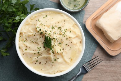 Photo of Delicious mashed potato with parsley served on wooden table, flat lay