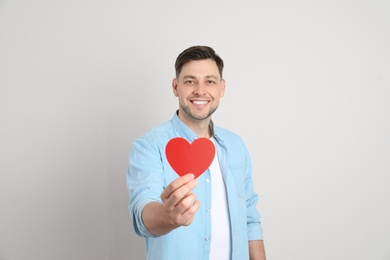 Photo of Portrait of man with paper heart on light background