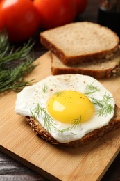 Photo of Tasty sandwich with fried egg on wooden table, closeup. Space for text