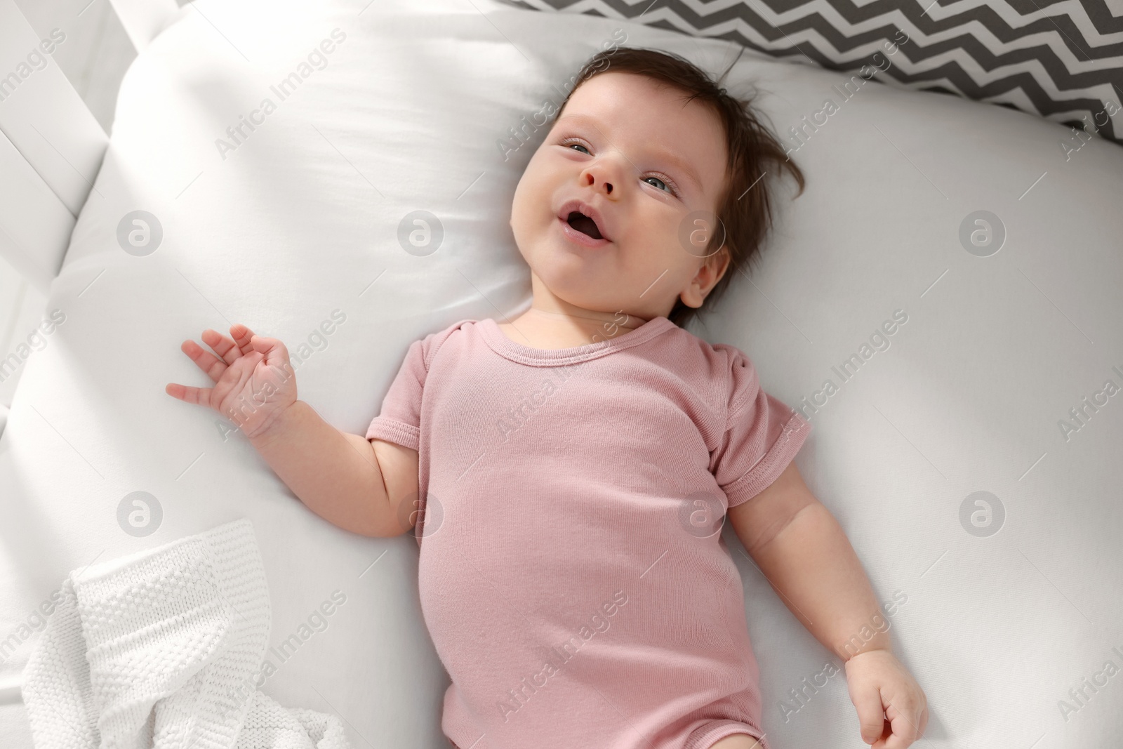 Photo of Cute little baby lying on bed, top view