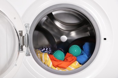 Photo of Green dryer balls and clothes in washing machine drum