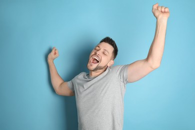 Portrait of sleepy man yawning on turquoise background