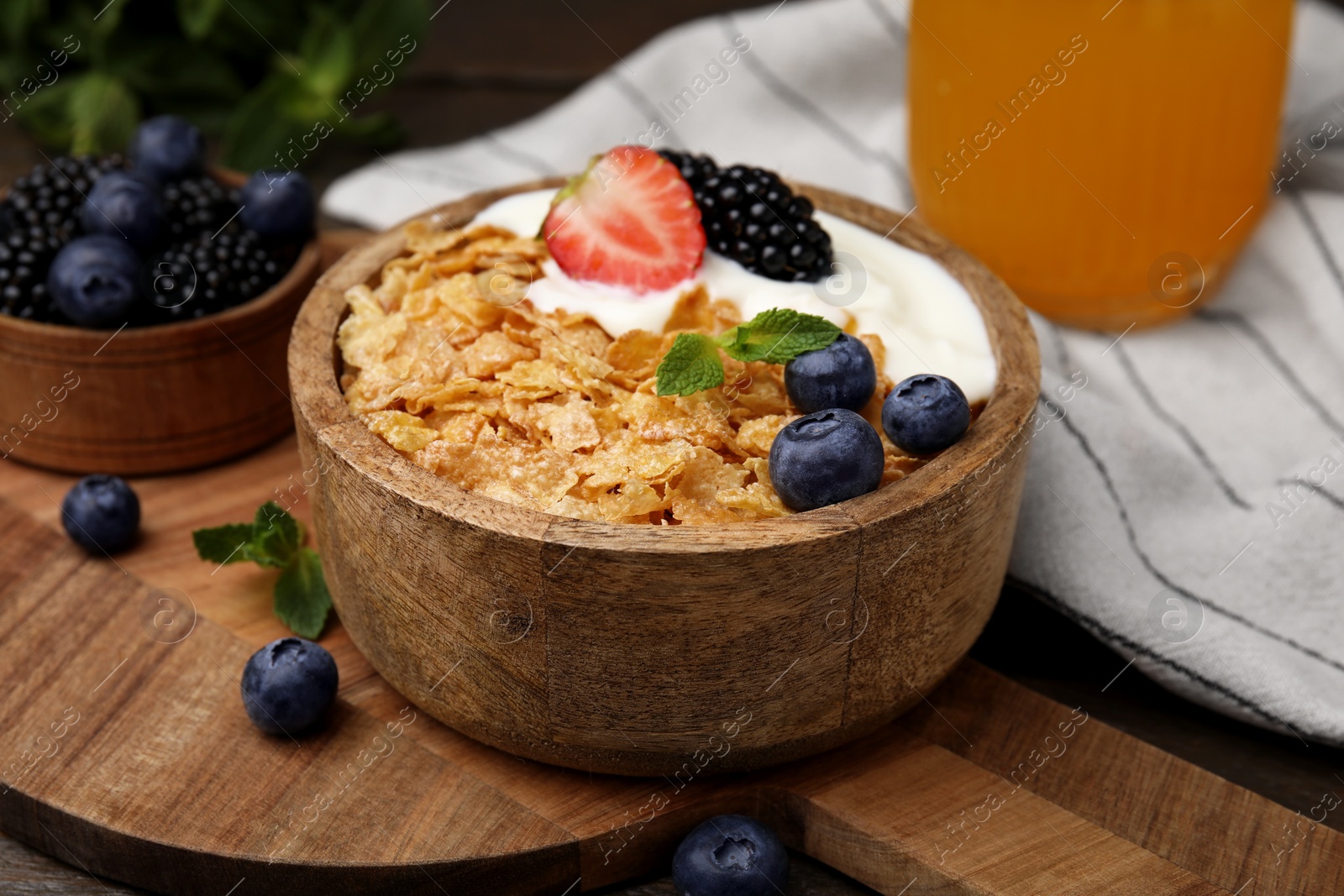 Photo of Delicious crispy cornflakes, yogurt and fresh berries in bowl on table, closeup. Healthy breakfast
