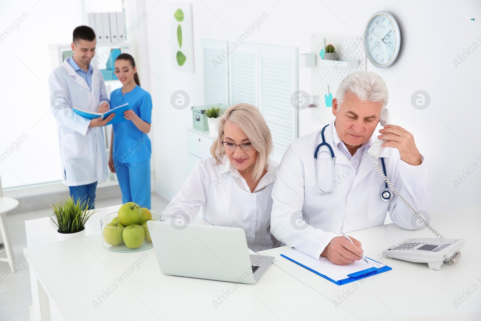 Photo of Mature female receptionist and senior male doctor working in hospital