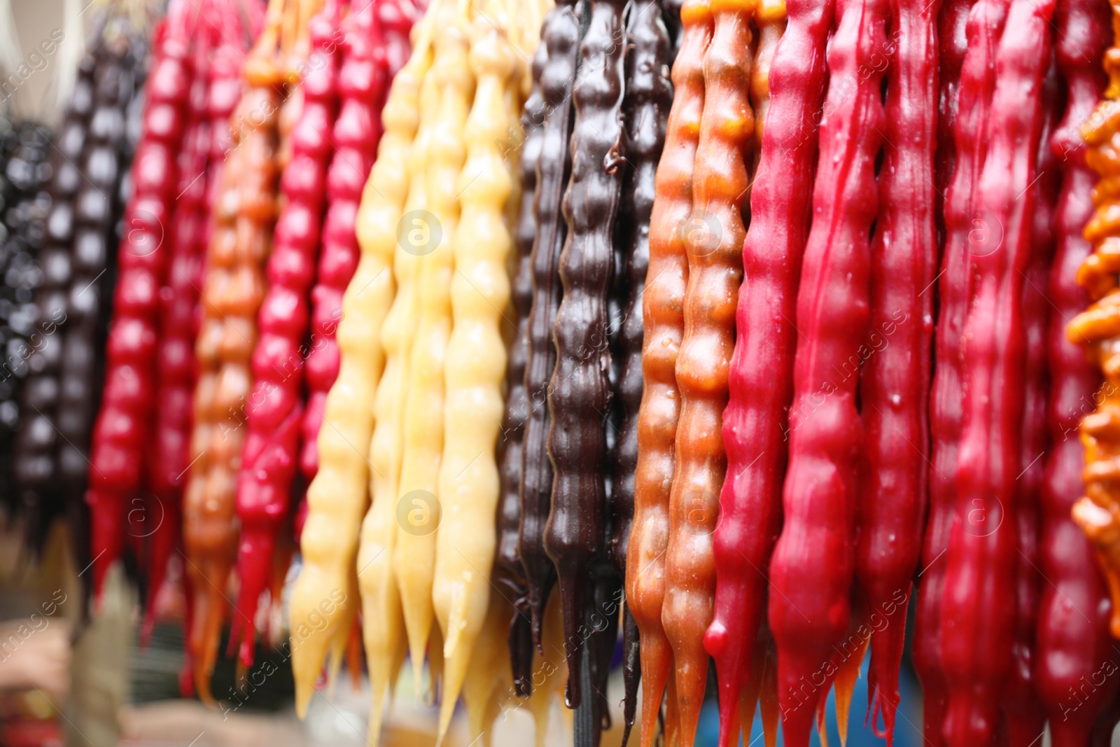 Photo of Bunches of different delicious churchkhelas at market, closeup