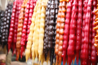 Photo of Bunches of different delicious churchkhelas at market, closeup