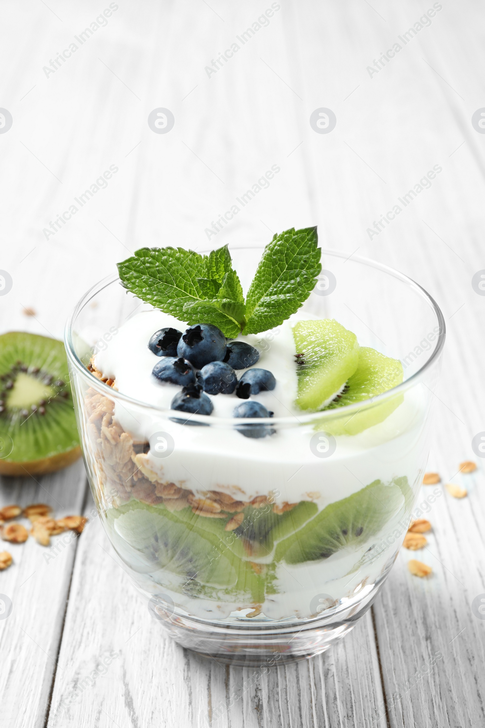 Photo of Tasty homemade granola dessert on white wooden table. Healthy breakfast