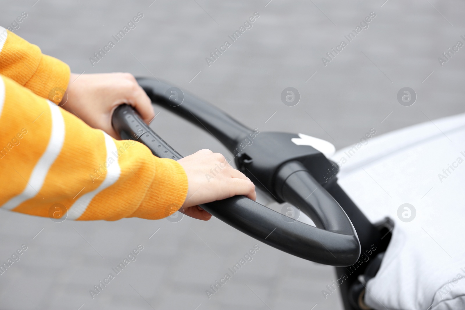 Photo of Nanny with baby in stroller walking on city street, closeup