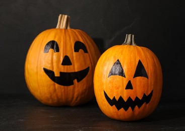 Photo of Pumpkins with drawn spooky faces on dark background. Halloween celebration