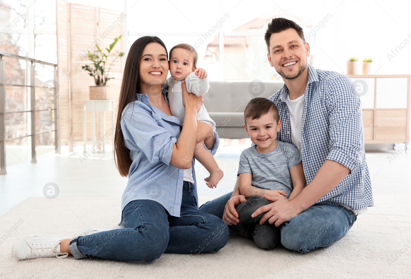 Photo of Happy couple with children sitting on floor at home. Family weekend