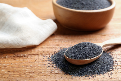 Poppy seeds and spoon on wooden table