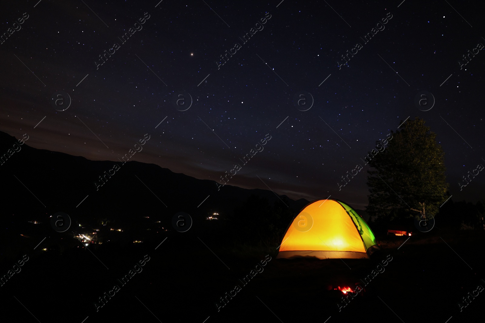 Photo of Beautiful view of mountain landscape with glowing camping tent at night