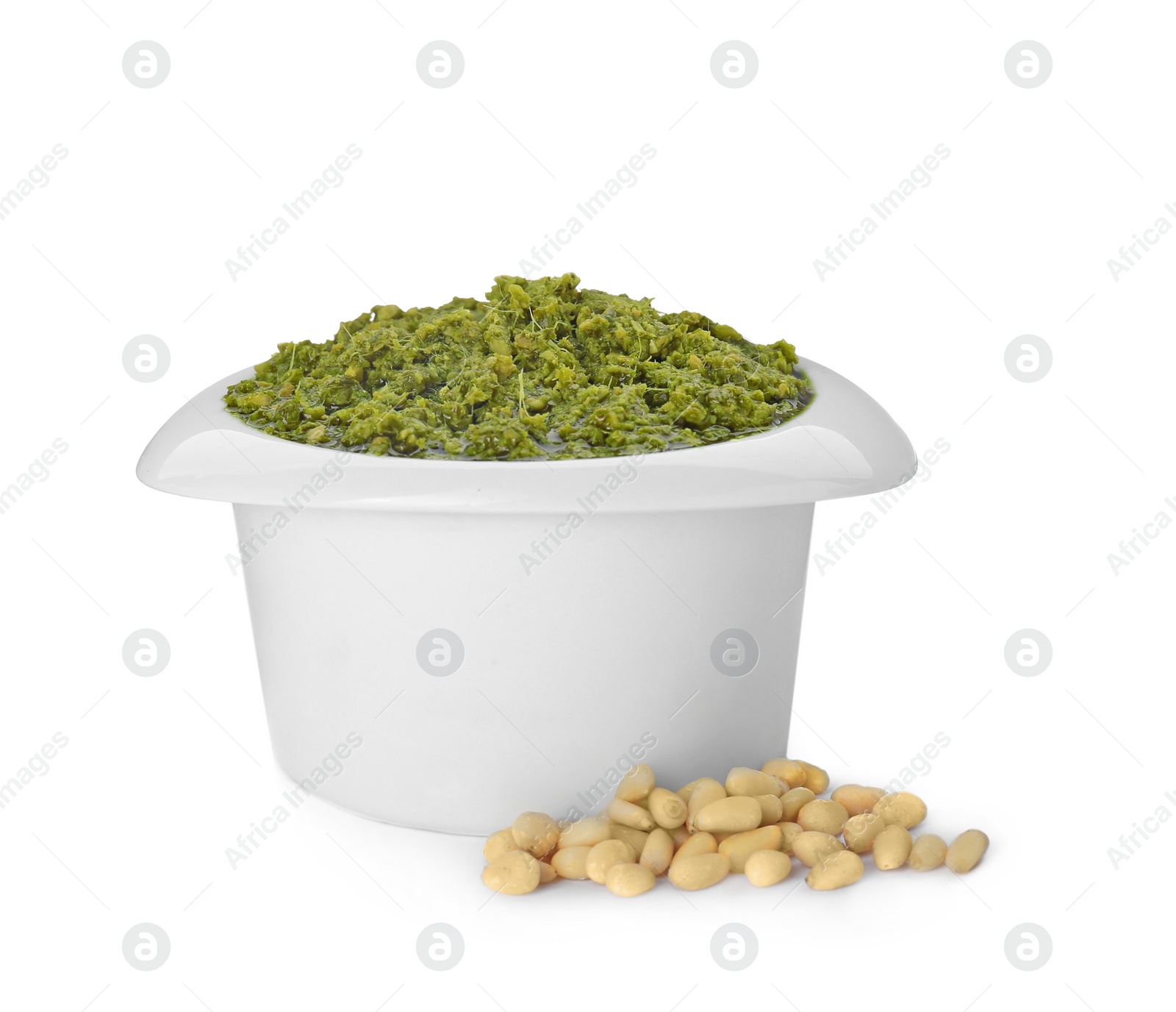Photo of Delicious pesto sauce in bowl and pile of pine nuts isolated on white