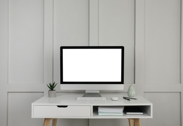 Photo of Modern computer, decor and office supplies on white wooden table near molding wall