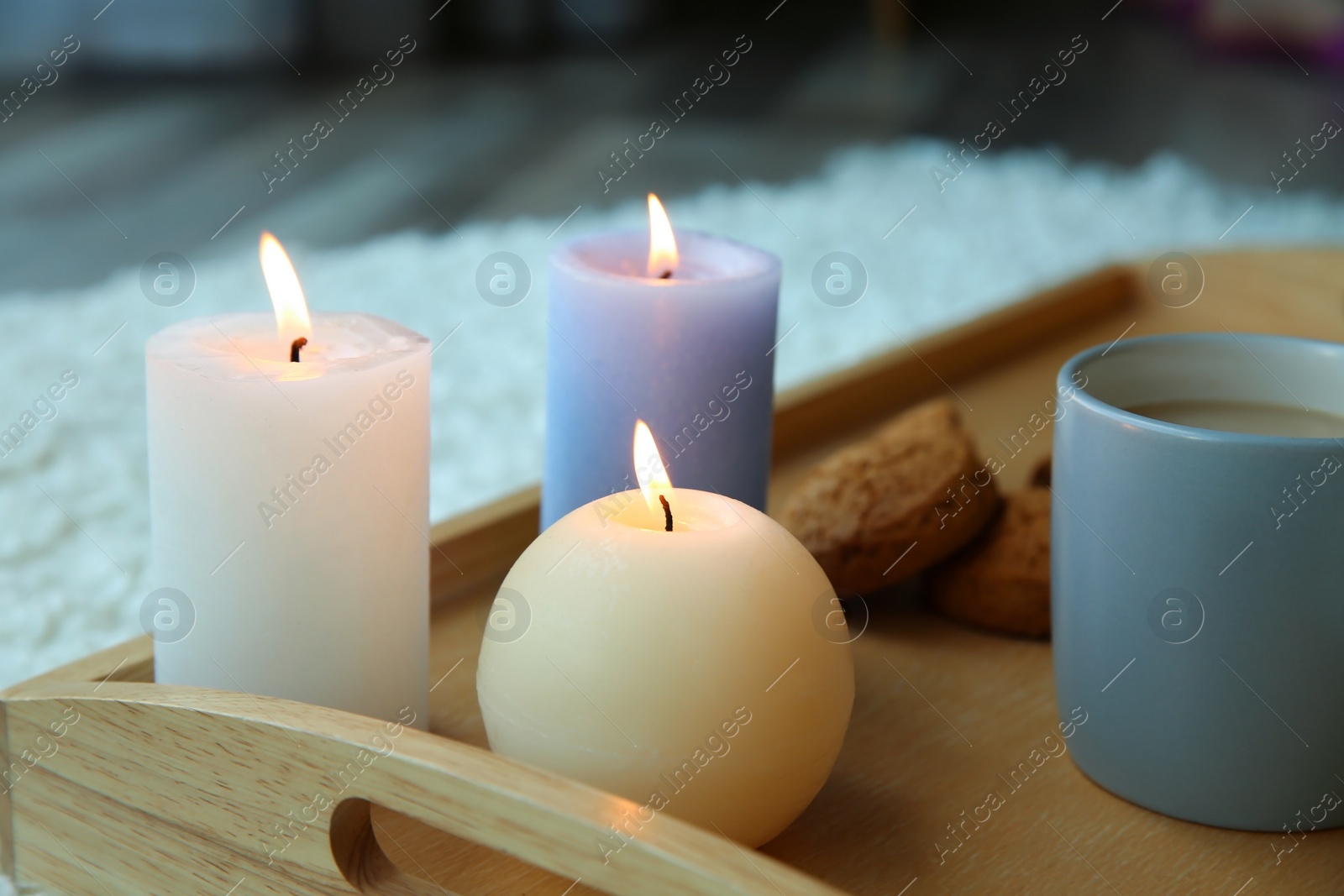 Photo of Burning candles and cup of coffee on wooden tray