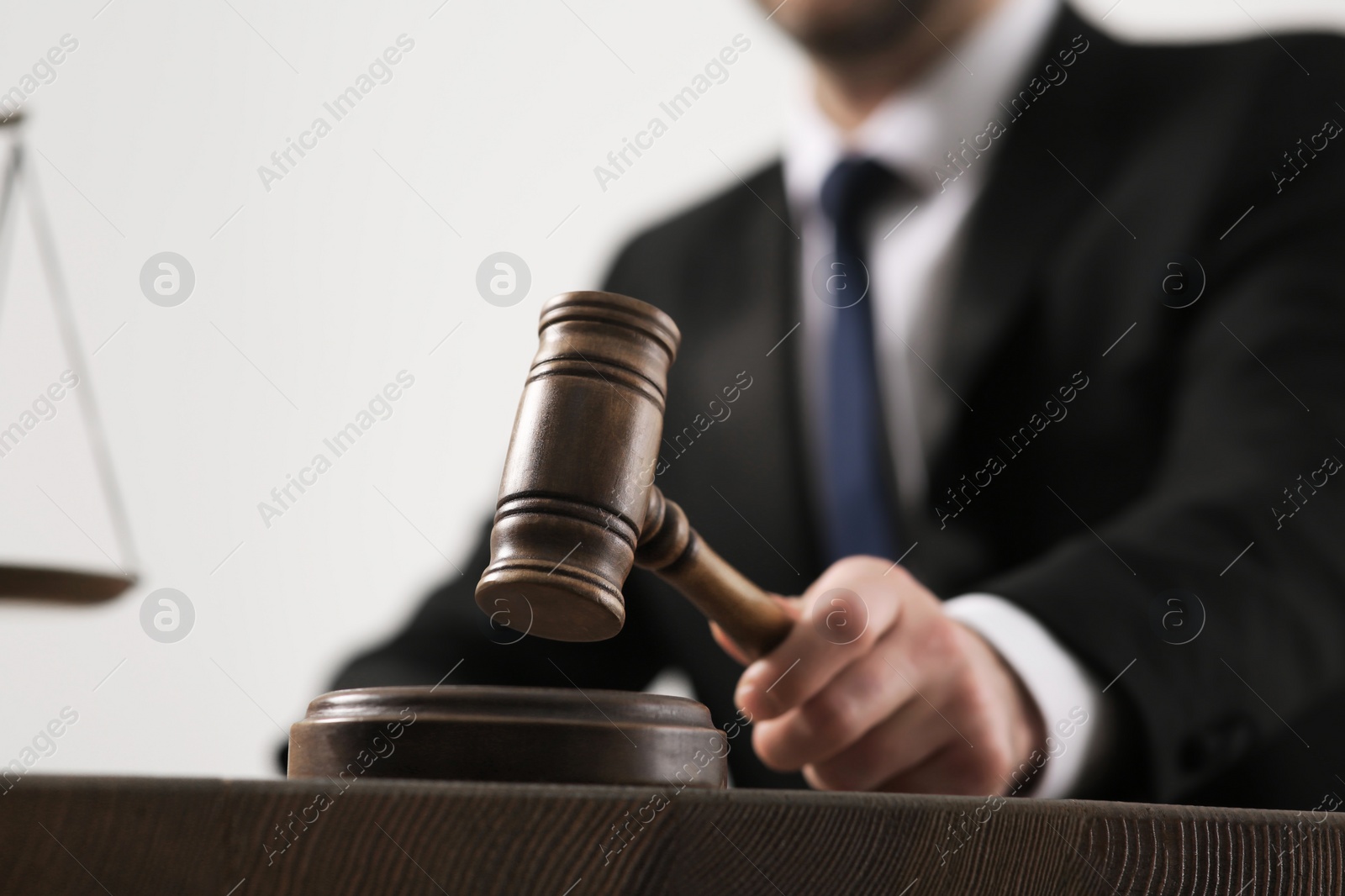 Photo of Law and justice. Closeup of judge with gavel at wooden table, selective focus