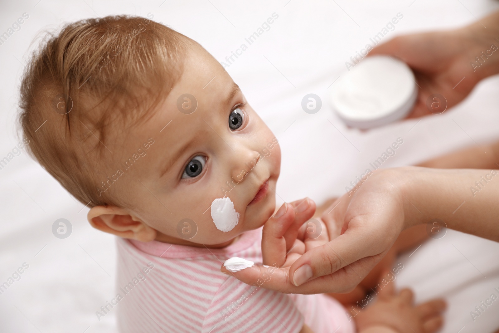 Photo of Mother applying moisturizing cream on her little baby, closeup