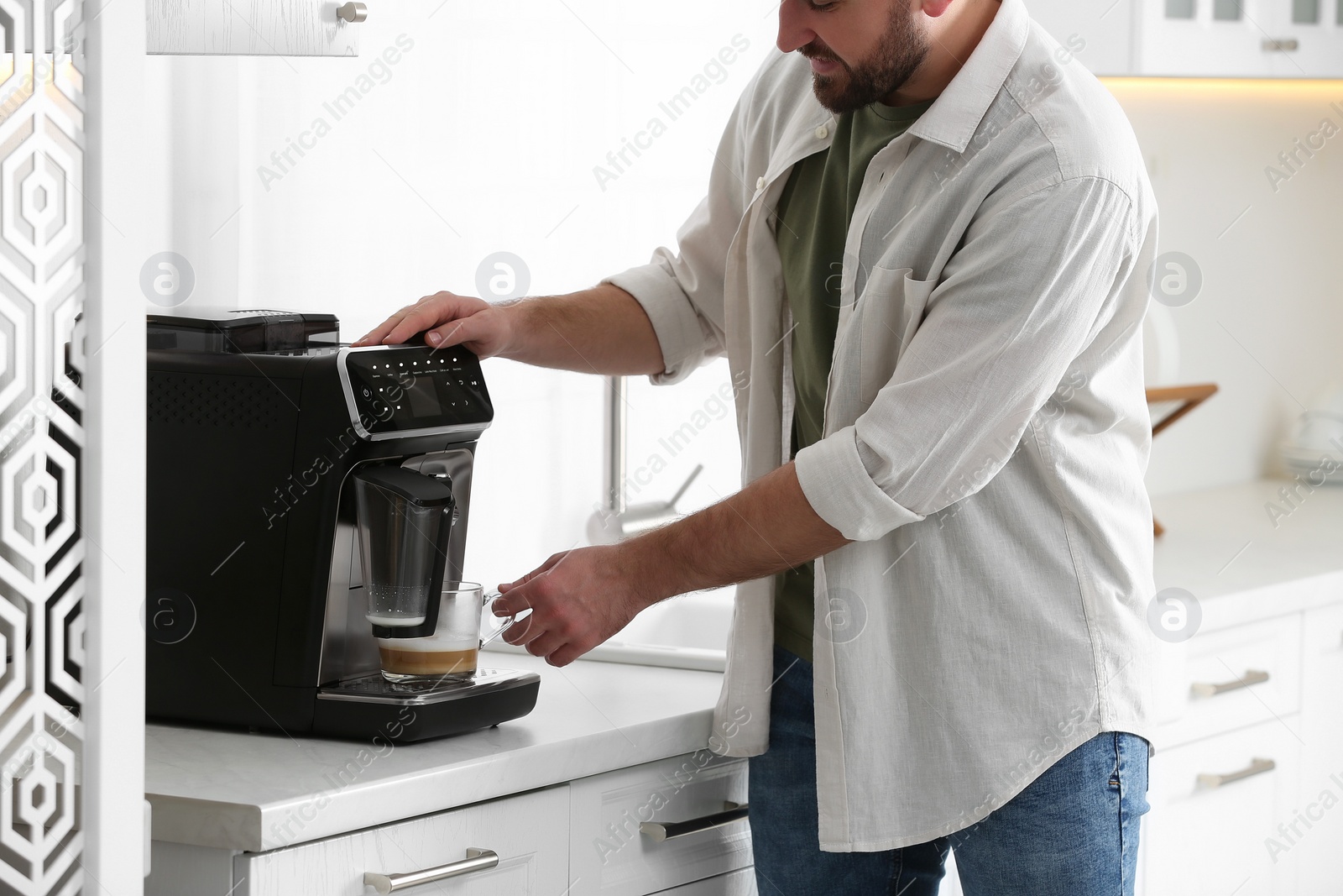 Photo of Young man preparing fresh aromatic coffee with modern machine in kitchen, closeup