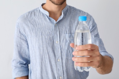 Photo of Man holding bottle of pure water on white background, closeup