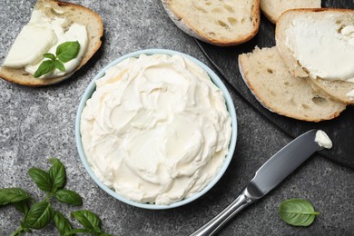 Photo of Tasty cream cheese, fresh bread and basil on grey table, flat lay