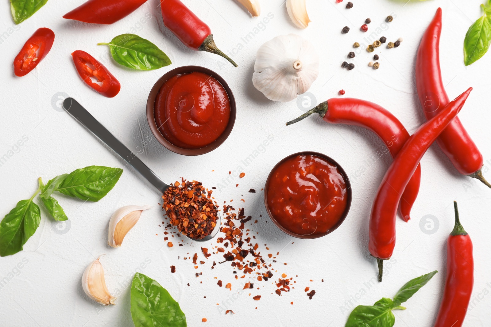 Photo of Flat lay composition with bowls of hot chili sauce and different spices on light background