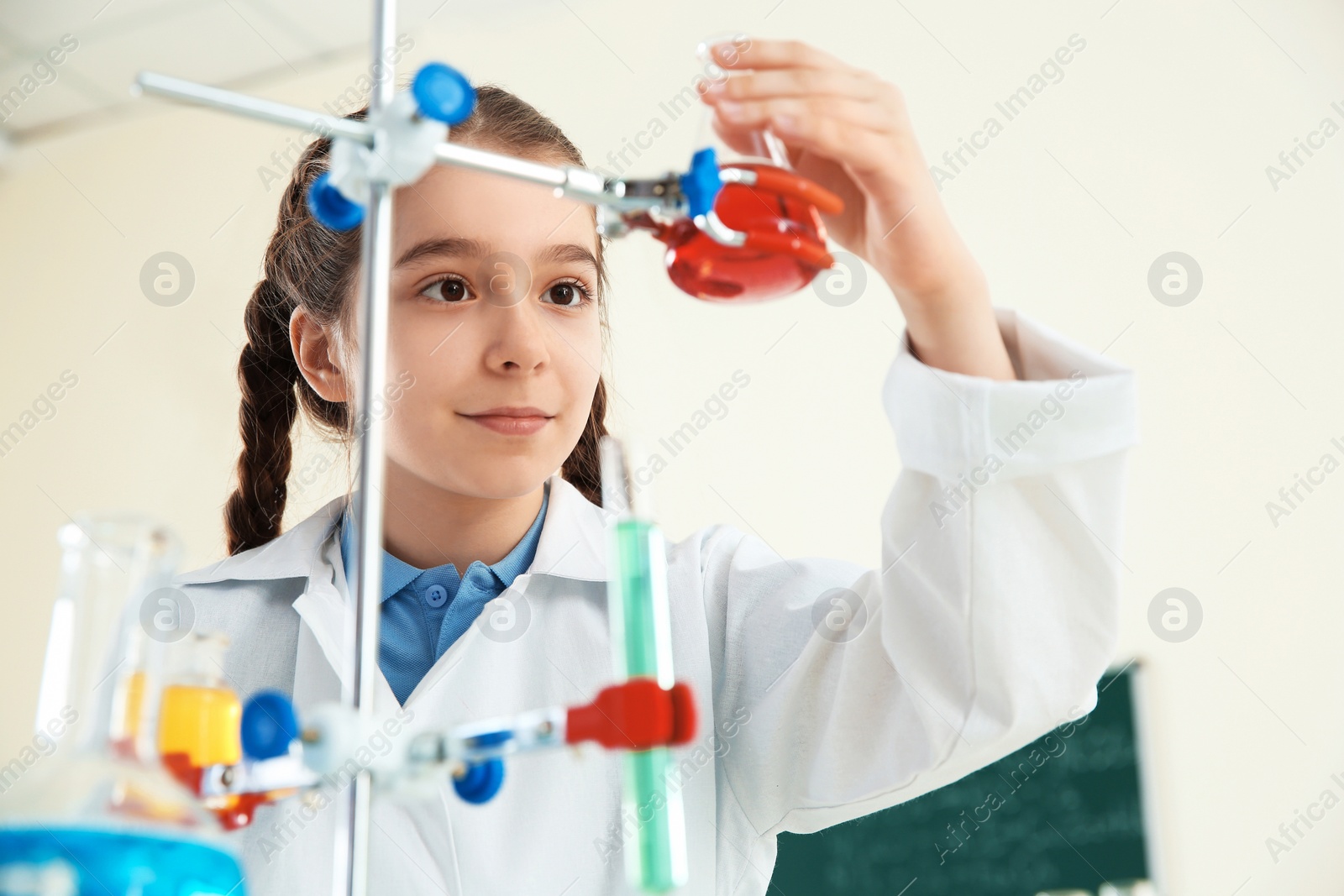 Photo of Smart pupil looking at flask with reagent on holder in chemistry class