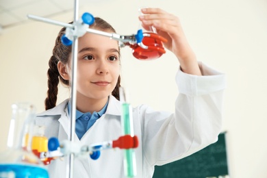 Photo of Smart pupil looking at flask with reagent on holder in chemistry class