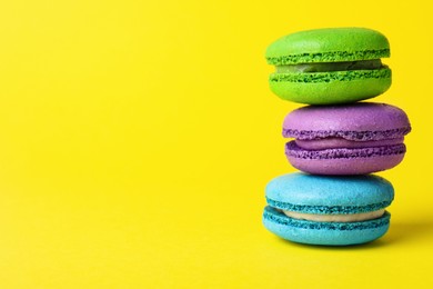 Photo of Delicious colorful macarons on yellow background, closeup, Space for text