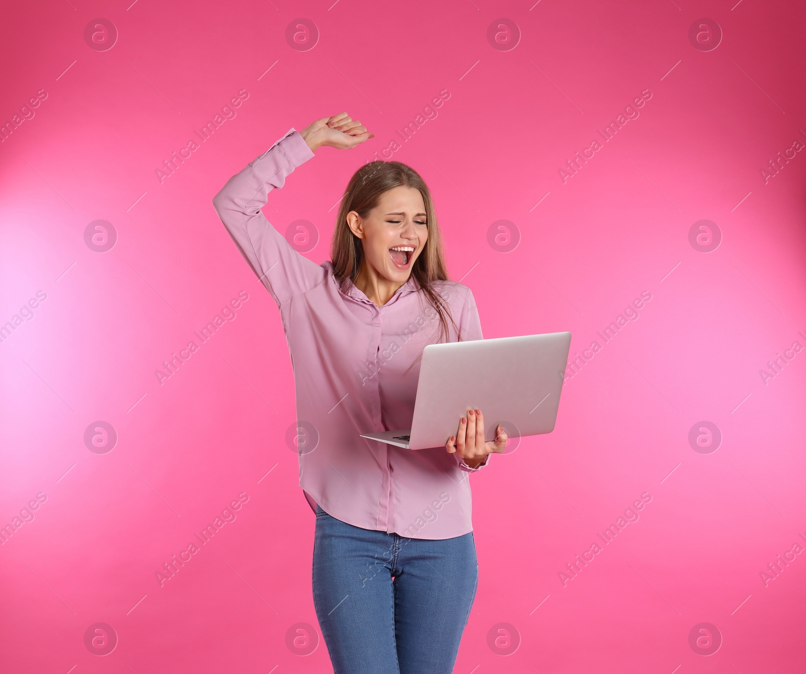 Photo of Emotional young woman with laptop celebrating victory on color background