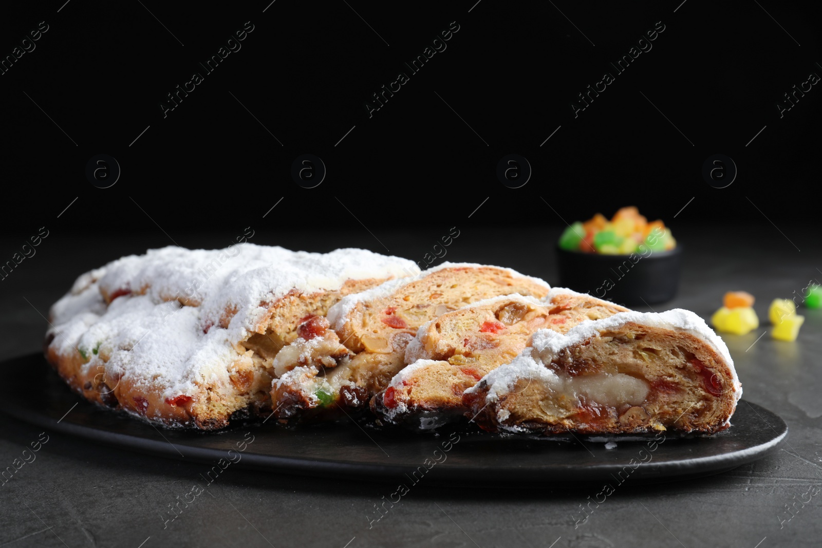 Photo of Traditional Christmas Stollen with icing sugar on black table