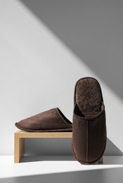 Photo of Pair of brown slippers and wooden stand on floor