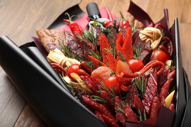 Photo of Beautiful edible bouquet with meat, cheese and vegetables on wooden table, closeup